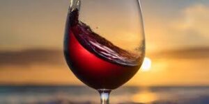 chilled red wine in a glass with the sunset behind it