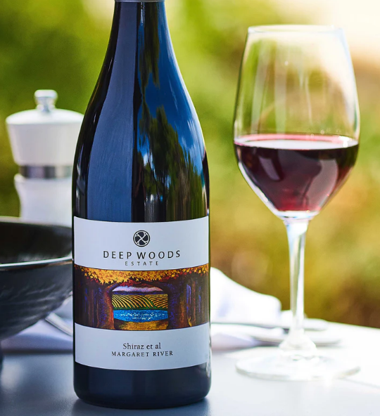 bottle of deep woods shiraz et al with a glass sitting next to it on a table. Wine is from the Margaret River wine region of Western Australia.